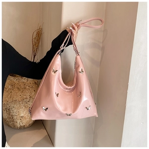 Dettaglio borsa hobo rosa in ecopelle con ciondoli a farfalla argento e tracolla