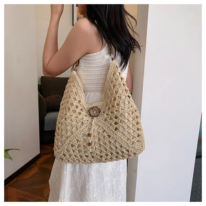 Detail of hand-woven straw shoulder bag with wooden flower button on summer dress