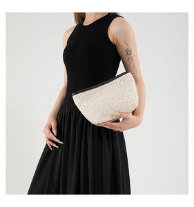 Detailed close-up of woven straw handbag with a black contrast zipper closure