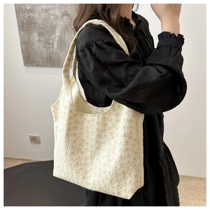Detail of off-white lace embroidery pattern on a minimalist hobo style shoulder bag