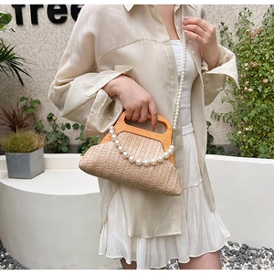 Detail of hand-woven straw bag with wooden handle and decorative pearl bead strap