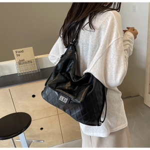 Detail of black quilted PU leather tote bag featuring a silver metal twist lock closure