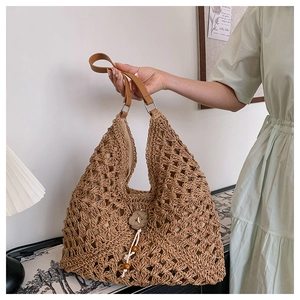 Close-up of handmade straw shoulder bag featuring wooden flower button and bead fringe