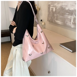 Dettaglio della borsa hobo rosa in ecopelle con farfalle d'argento su una modella