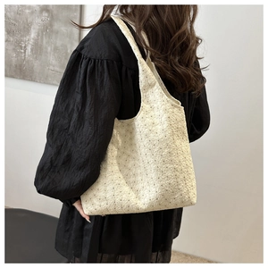 Detail view of off-white lace embroidered tote bag with floral patterns on a model shoulder