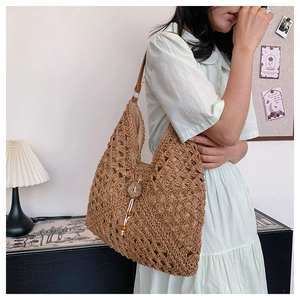 Detail of a brown woven straw shoulder bag with wooden flower button and beaded tassel