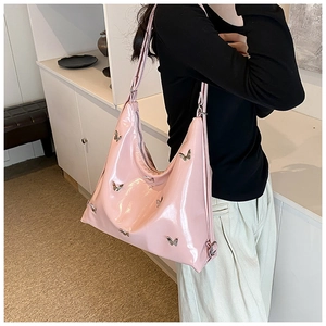 Dettaglio della borsa in pelle verniciata rosa con piccoli accenti a farfalla in metallo