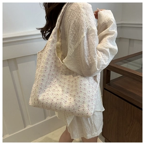 Detail of trendy off-white tote bag featuring delicate pink floral embroidery on thick fabric
