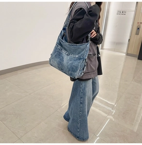 Detail van grote denim draagtas met functionele voorzakken en verstelbare schouderriem