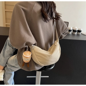 Detail of beige crescent nylon crossbody bag with cute coffee cup plush charm accessory