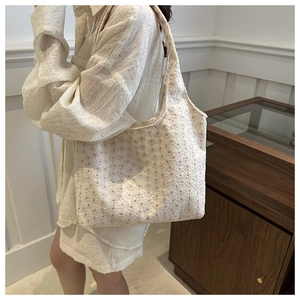 Detail of cream canvas tote bag with pink floral embroidery on a shoulder strap model