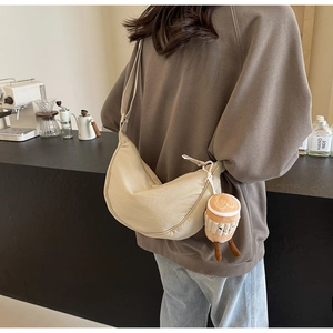 Detail of beige crescent crossbody bag with cute latte coffee plush charm on strap