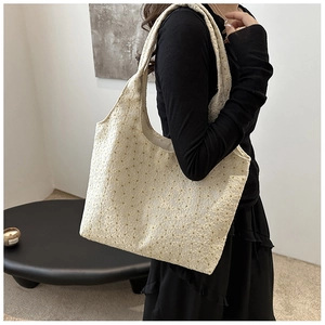 Close-up of cream lace tote bag with floral embroidery and textured fabric detail