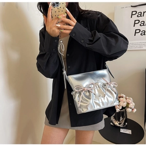 Detailed macro view of metallic silver PU shoulder bag with pink decorative bows and texture