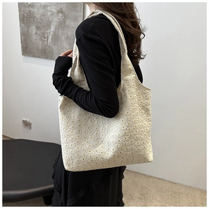 Close-up of beige tote bag featuring delicate floral lace embroidery and spacious design