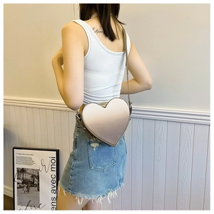 Détail du sac à bandoulière argenté en forme de cœur avec finition métallisée