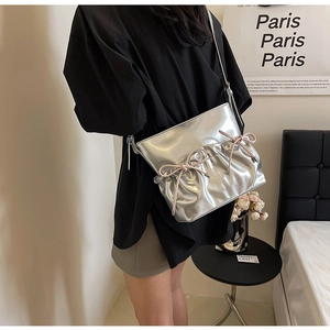 Detail of silver metallic PU shoulder bag with pleated texture and pink bow accents