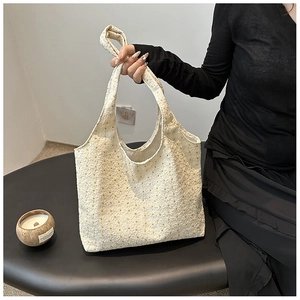 Close-up of cream white lace crochet tote bag featuring intricate floral textures and patterns