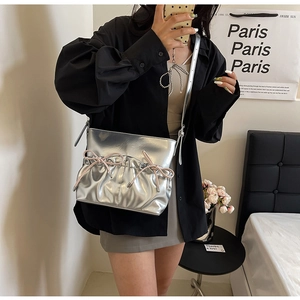 Close-up of silver PU crossbody bag featuring elegant pink bows and metallic褶皱 finish