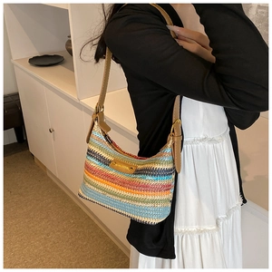 Détail du sac à bandoulière en paille tressée arc-en-ciel avec lanière en cuir sur modèle