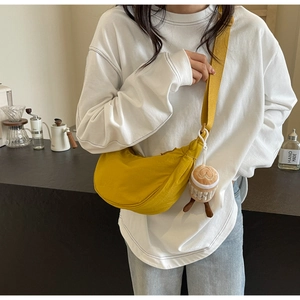 Close-up of a yellow canvas half-moon hobo bag with a cute coffee cup plush charm