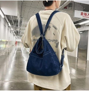 Detail of dark blue denim backpack showing large capacity and contrast stitching