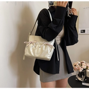 Detailed view of cream PU crossbody bag featuring unique double bow drawstring pockets