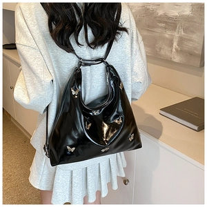 Vista posteriore di una borsa tote Y2K in pelle verniciata nera con farfalle in metallo