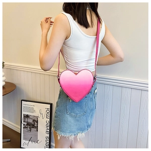 Vue détaillée du sac à bandoulière en forme de cœur dégradé rose porté par un mannequin