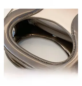 Détail de la texture cuir PU brillant et des surpiqûres contrastées sur l'anse du sac