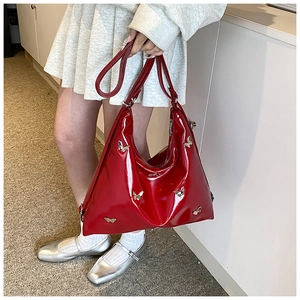 Dettaglio di borsa tote in pelle verniciata rossa con ciondoli a farfalla