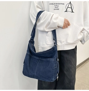 Detail of blue denim hobo bag with white contrast stitching and silver metal hardware