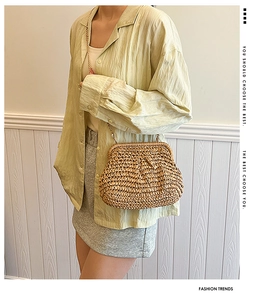 Détail d'un sac coquillage en paille tressée avec chaîne dorée sur mannequin femme