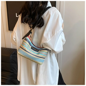 Détail du sac à bandoulière tissé coloré avec motif rayé et bandoulière en cuir noir