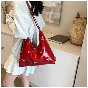 Dettaglio borsa hobo in PU rosso con ciondoli a farfalla argento portati a spalla