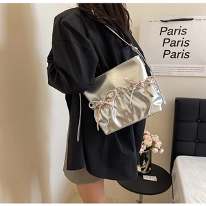 Detail of silver metallic PU shoulder bag featuring pink bows and stylish pleats