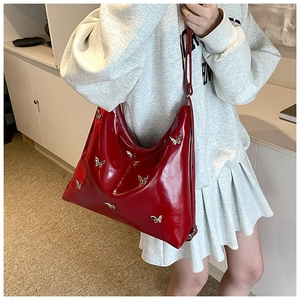 Dettaglio della borsa hobo in pelle PU rossa lucida con decorazioni a farfalla d'argento