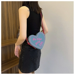 Vue lifestyle montrant le sac bandoulière en denim en forme de cœur avec lettrage rose