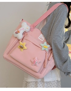 Detailed side view of pink nylon tote with colorful star patches and bone pendant