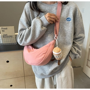 Detailed view of pink crescent nylon crossbody bag with cute coffee cup plush charm