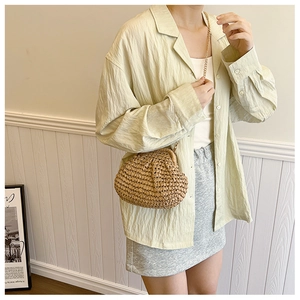 Vue détaillée de la texture de fibre tressée et chaîne dorée du sac paille coquille