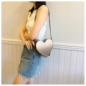 Détail du sac bandoulière en forme de cœur avec dégradé métallique porté par un modèle