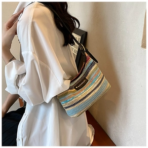 Détail d'un sac à bandoulière tissé multicolore avec sangle en cuir et plaque logo