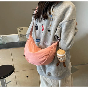 Pink canvas half-moon crossbody bag with a cute coffee cup plush charm on a shoulder strap