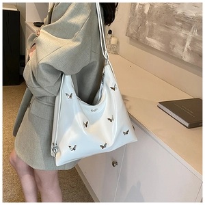 Dettaglio borsa hobo bianca in PU con farfalle metalliche 3D indossata da modella chic