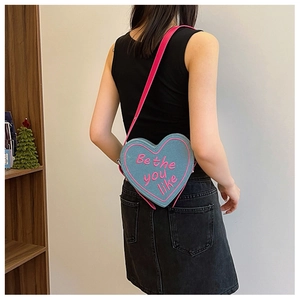 Détail du sac à main cœur en denim bleu avec bandoulière rose et broderie