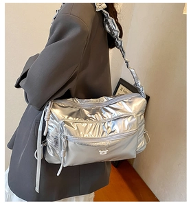 Detail of silver metallic puffer crossbody bag with drawstring strap and bear logo