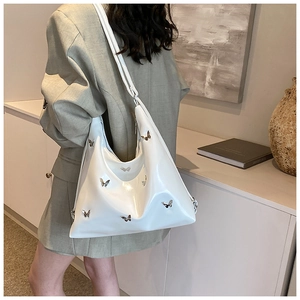 Dettaglio della borsa hobo in PU bianco con ciondoli a farfalla su una modella