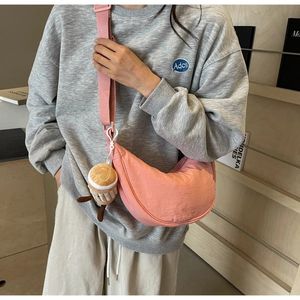 Pink nylon crescent crossbody bag with coffee cup plush charm worn by model