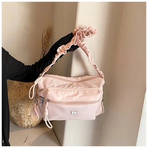 Detailed view of pink nylon crossbody bag with ruffled shoulder strap and bear logo